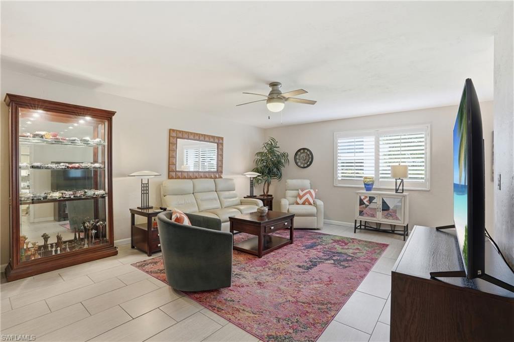 Expansive living area featuring light-toned tile flooring, a ceiling fan with integrated lighting, and neutral wall tones