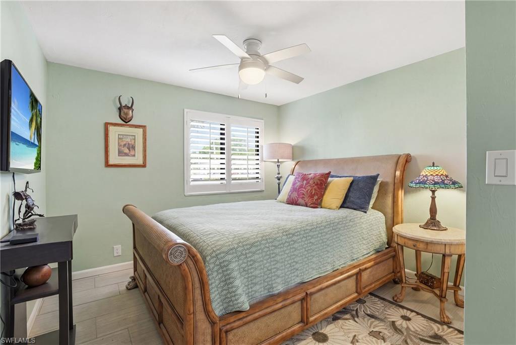 Bedroom with light green walls and wood-finish flooring