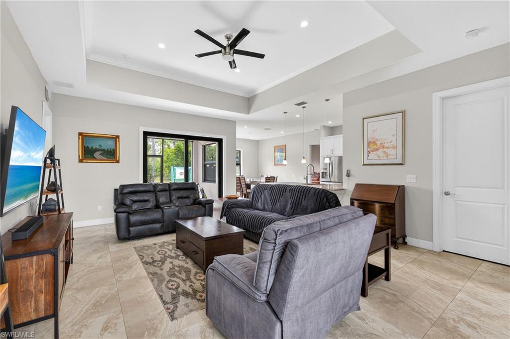 Spacious living area featuring large format tile flooring, crown molding, recessed lighting, and a modern ceiling fan