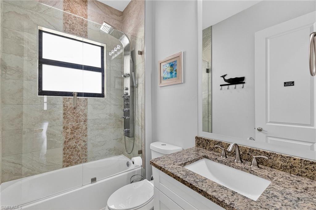 Bathroom featuring a built-in bathtub with glass shower enclosure, a multi-function shower panel, and a window