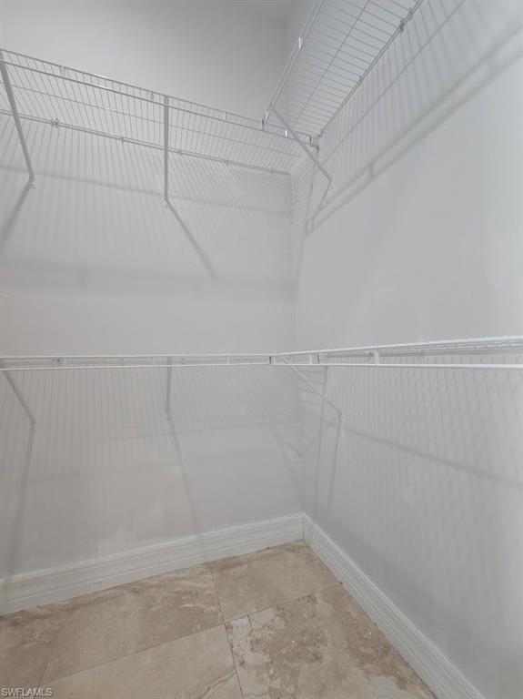 Walk-in closet featuring wire shelving, wire hanging rods, neutral wall paint, and square tile flooring