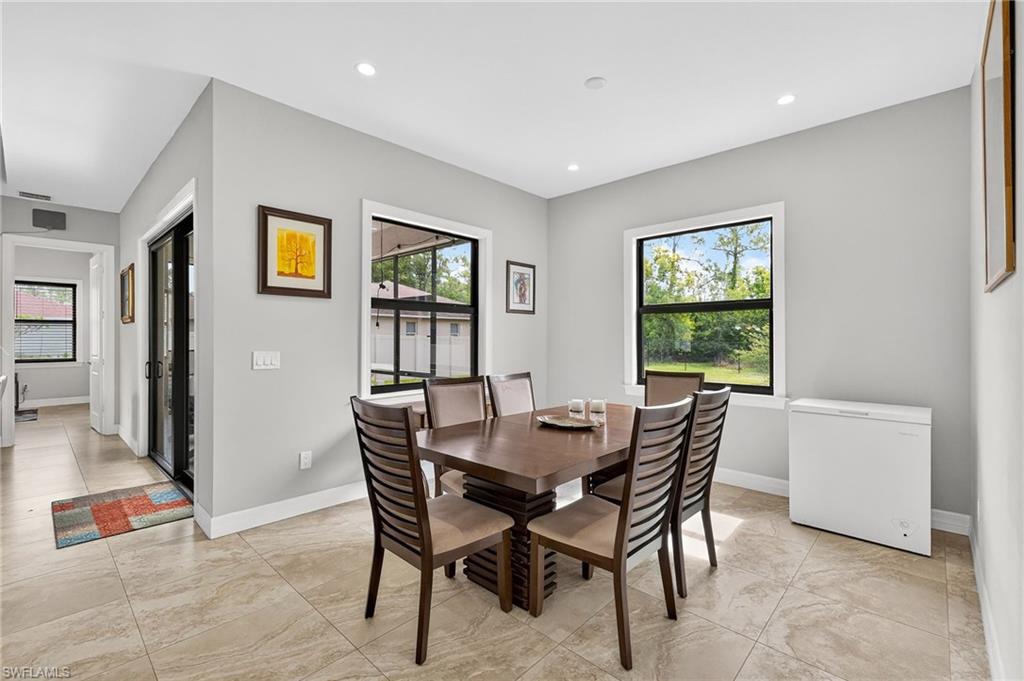 Spacious dining area featuring neutral wall tones, recessed lighting, large windows, and tile flooring