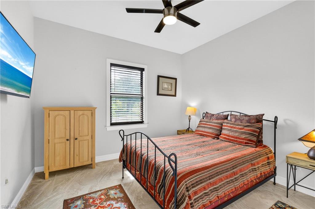 Bedroom featuring neutral wall paint, tiled flooring, a ceiling fan with integrated lighting, and a single window with blinds