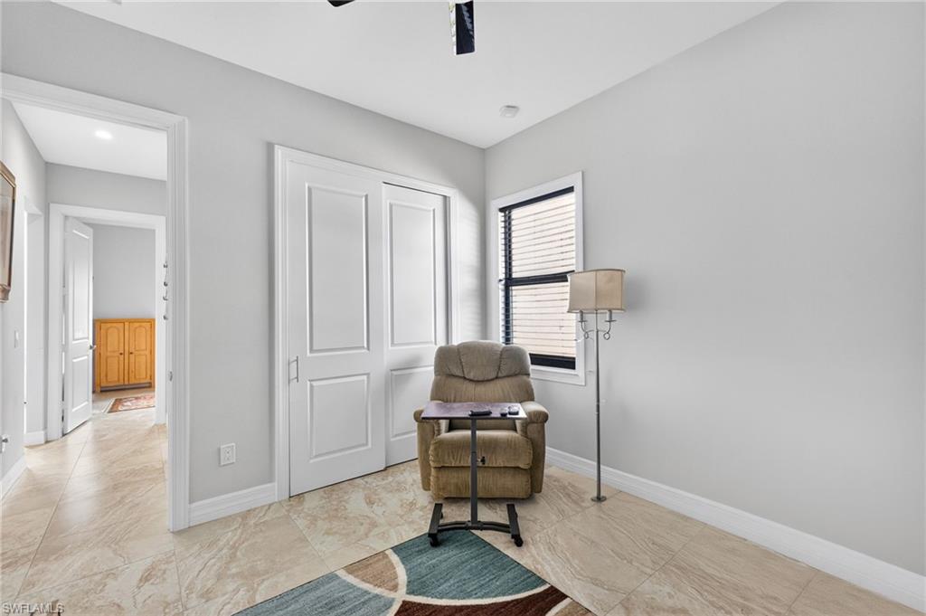 Light-toned tile flooring extends throughout this room, featuring light gray walls and a window with horizontal blinds