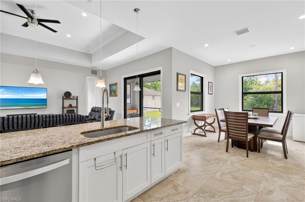 Kitchen island with a granite-style countertop and undermount sink, complemented by white shaker-style cabinetry and a stainless steel dishwasher