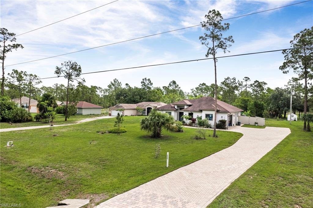 Expansive property featuring a paved driveway, mature trees, and a well-maintained lawn