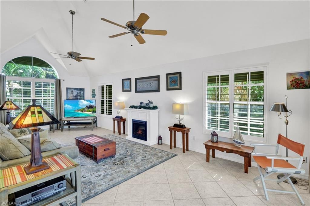 Spacious living area featuring vaulted ceilings, tile flooring, and multiple windows with plantation shutters