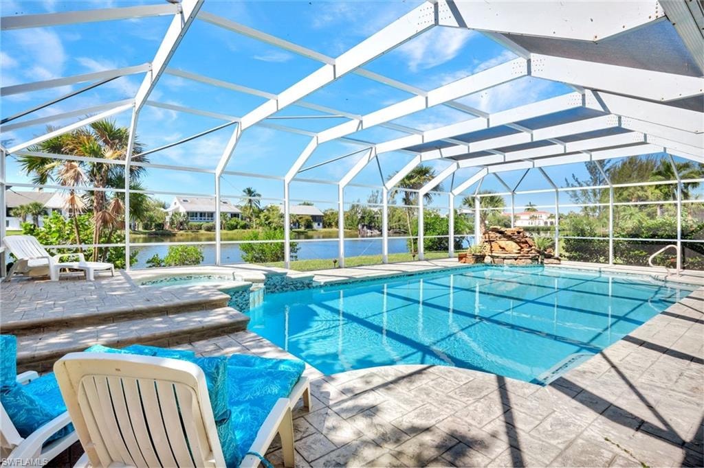 Screened lanai featuring a swimming pool, integrated spa, and decorative rock waterfall