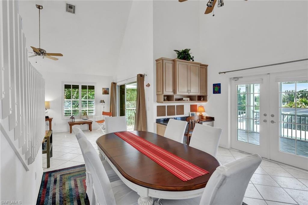 Dining area featuring vaulted ceilings, light-finish tile flooring, and a built-in wet bar with wood-finish cabinetry