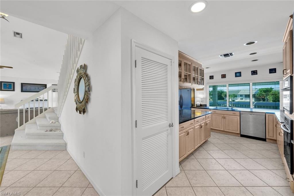 Kitchen featuring light wood cabinetry, dark countertops, and stainless steel appliances