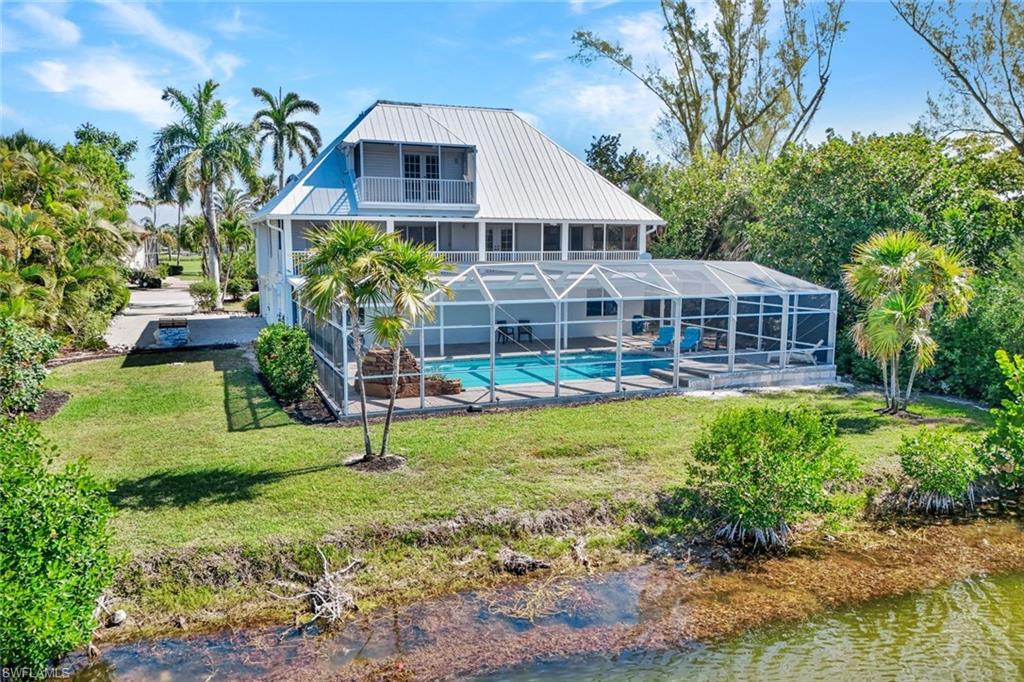 Two-story waterfront residence featuring a screened-in pool and an upper-level balcony