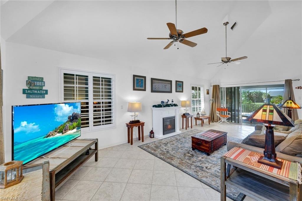 Spacious living area featuring vaulted ceilings, ceiling fans, and neutral tile flooring