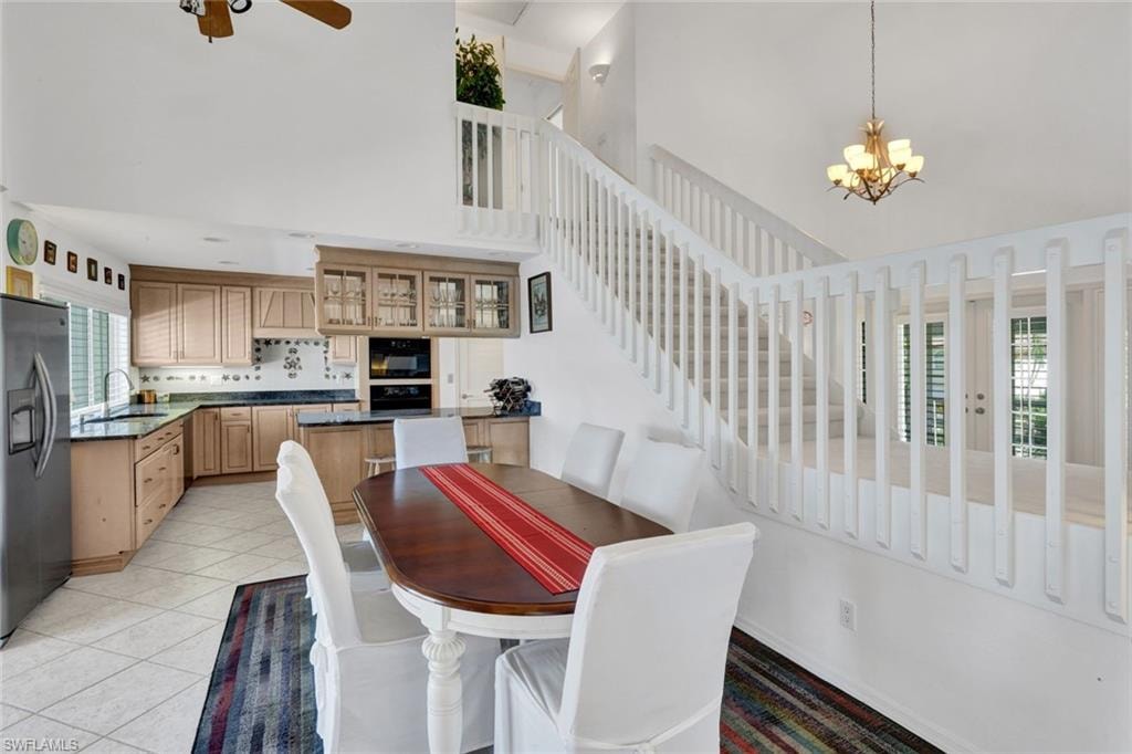 Two-story interior featuring a kitchen with wood cabinetry, dark countertops, and a white tile backsplash