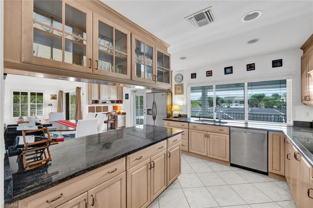 Light wood-finish cabinetry throughout featuring upper glass-front cabinets and dark stone countertops
