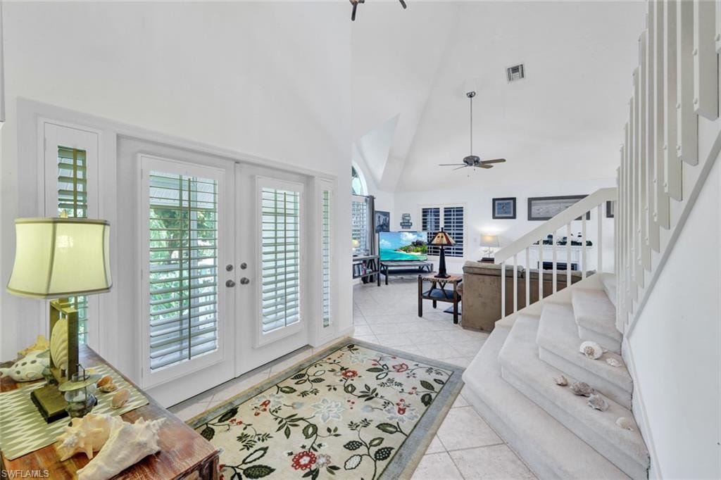 Entryway featuring double French doors with plantation shutters and side lites, vaulted ceilings, and tile flooring