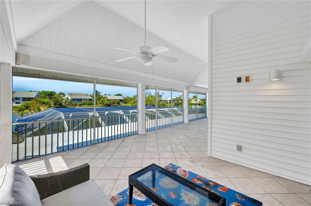 Screened lanai featuring a vaulted ceiling with a ceiling fan, tiled flooring, and a waterside perspective