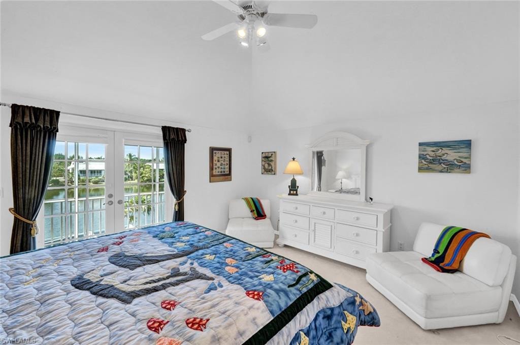 Vaulted ceiling with a ceiling fan, double glass doors with transom windows, and water views