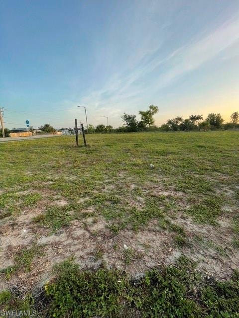Expansive cleared lot featuring partial ground cover and visible road frontage