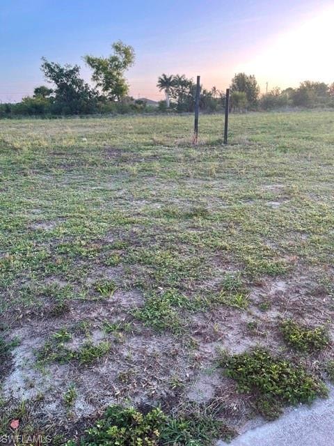 Expansive land parcel featuring existing ground cover, a flat topography, and clear boundaries with visible property markers