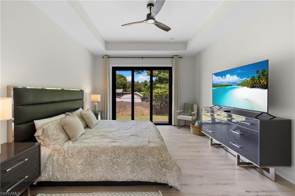 Spacious room featuring light-toned flooring, a tray ceiling, and a ceiling fan