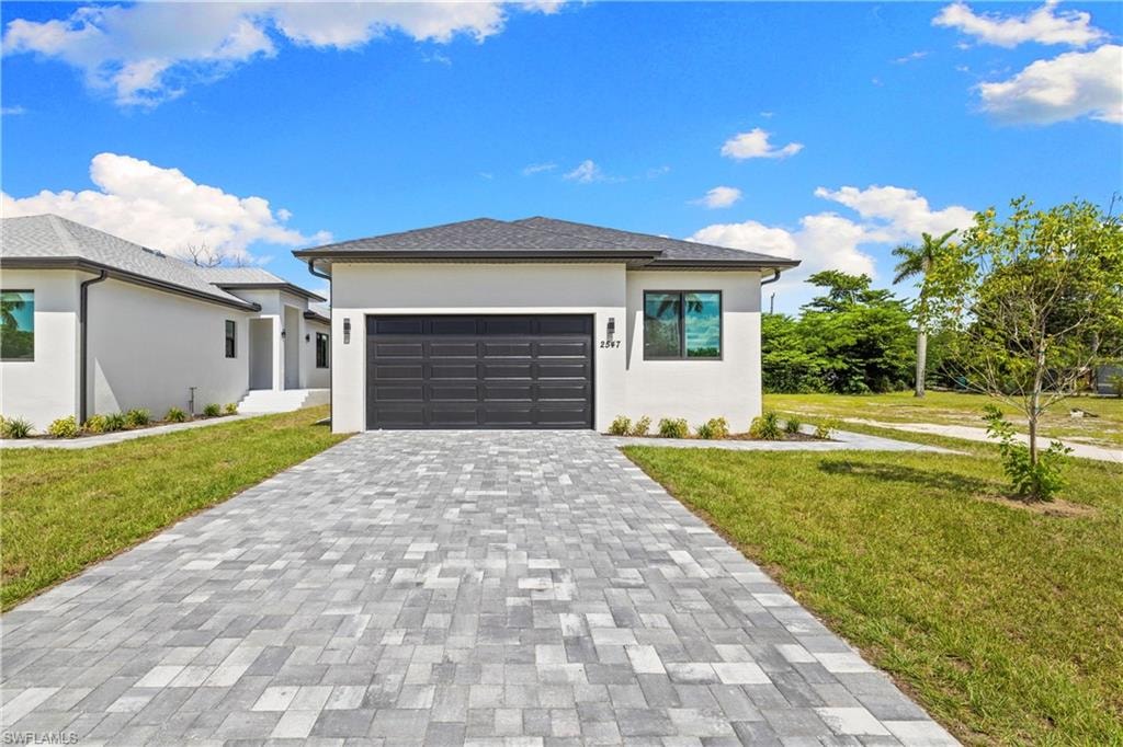 Contemporary exterior featuring a dark gray garage door, light stucco facade, and a gray shingle roof