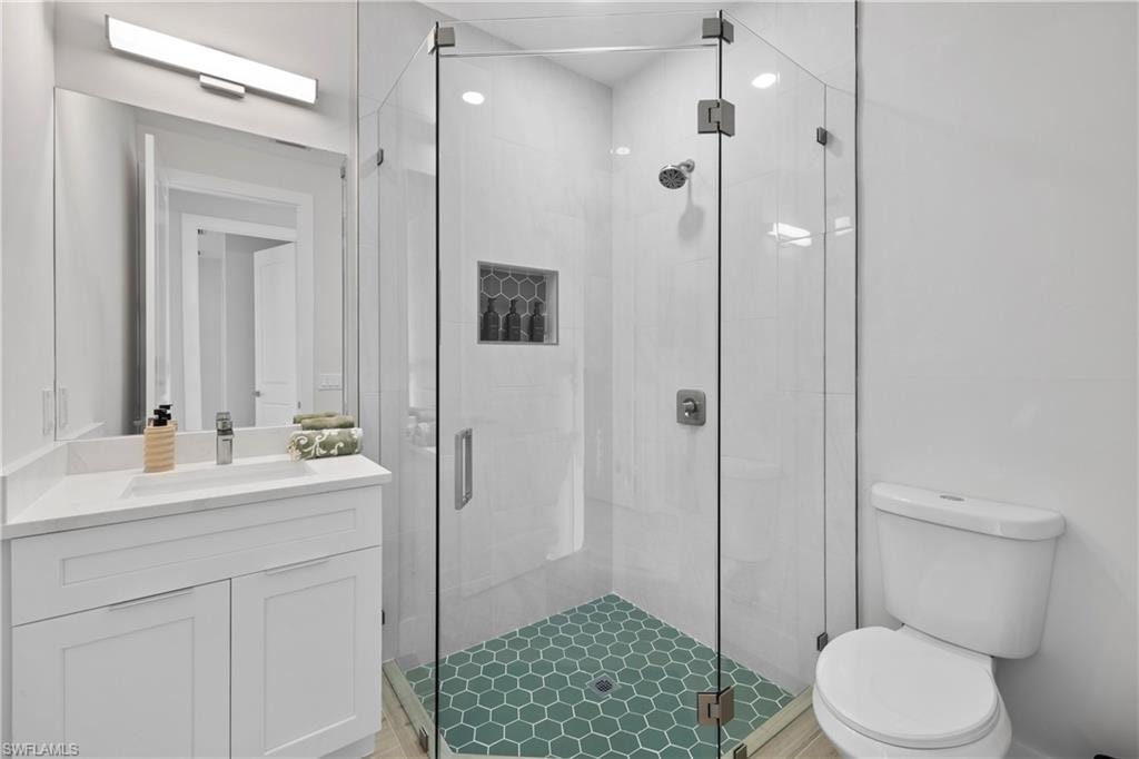 Glass-enclosed shower featuring white subway tile walls and a hexagonal green tile floor with a built-in niche