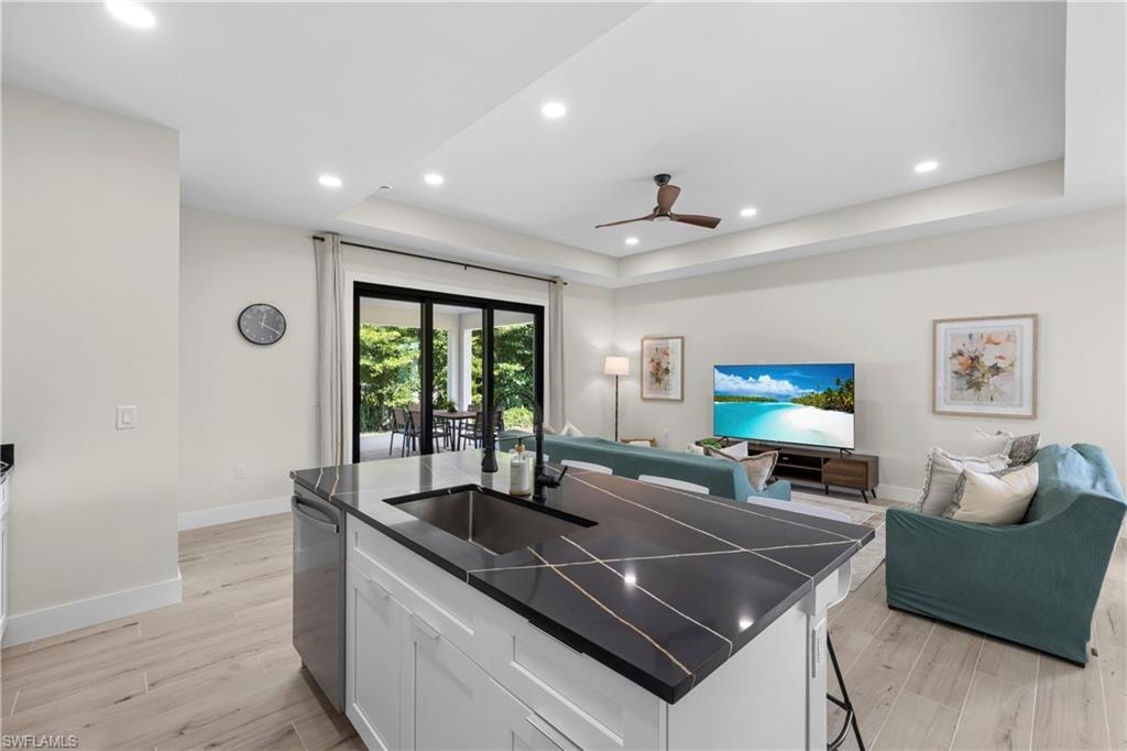 Kitchen island featuring a black countertop with veining, an undermount sink, and an integrated dishwasher