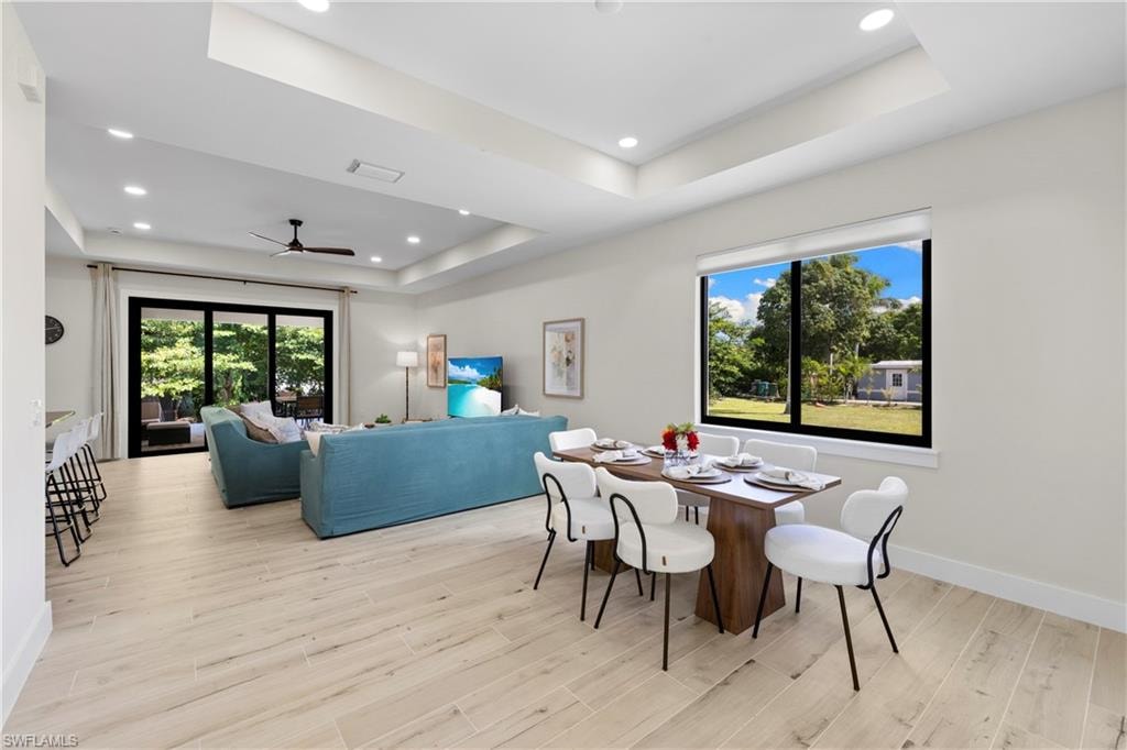 Open-concept living space featuring wood-finish flooring, recessed lighting, and tray ceilings