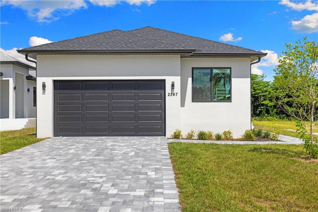 Contemporary single-story residence featuring a dark gray garage door, white stucco exterior, and a dark shingle roof