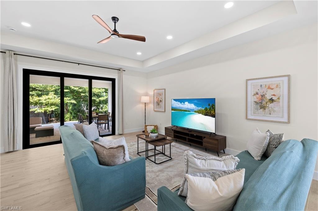 Living area with wood-finish flooring, recessed lighting, and a tray ceiling