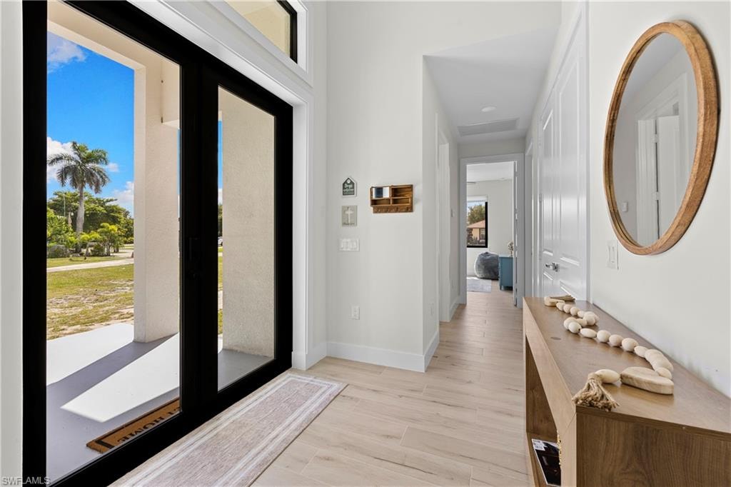 Entryway featuring black-framed glass double doors, wood-finish flooring, white baseboards, and a recessed ceiling
