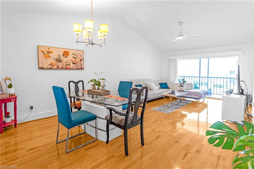 Open-concept living area with wood-finish flooring, a vaulted ceiling, and a contemporary ceiling fan