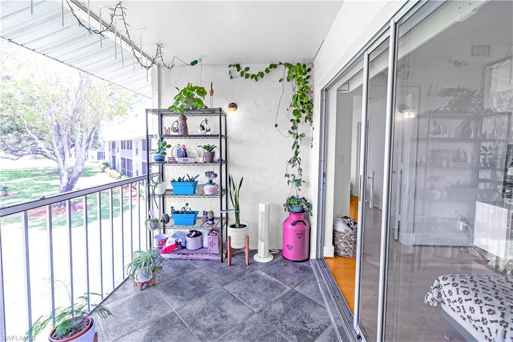 Balcony featuring a tile floor, white stucco wall, and metal railing