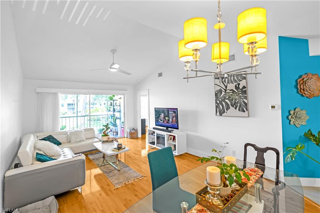 Vaulted ceiling living space featuring wood-finish flooring and a contemporary ceiling fan