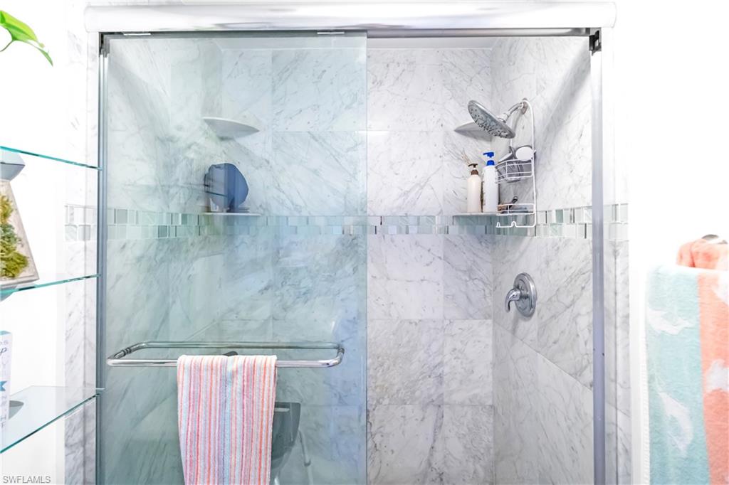 Frameless glass shower enclosure featuring a sliding door and a chrome towel bar