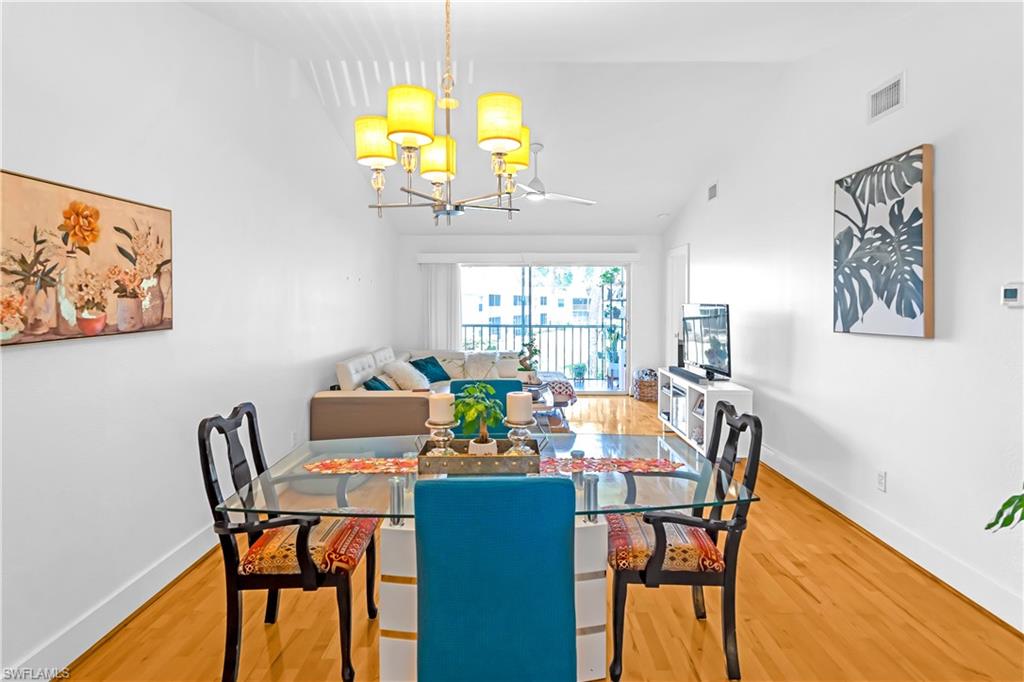 Open-concept living area featuring wood-finish flooring, white walls, and a vaulted ceiling