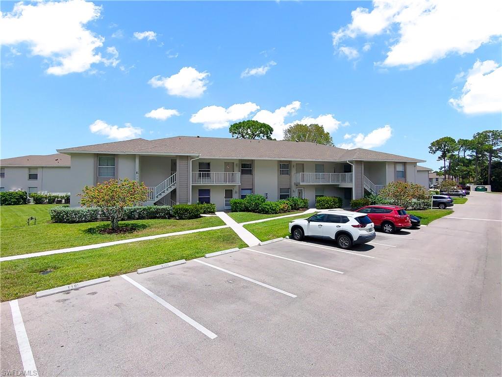 Multi-unit building featuring a light-toned exterior, multiple balconies, and exterior staircases