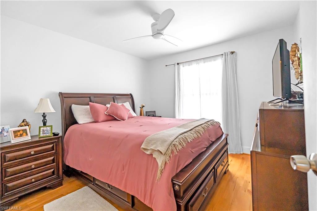 Bright interior space featuring light wood-finish flooring, a ceiling fan, and a window with white drapes