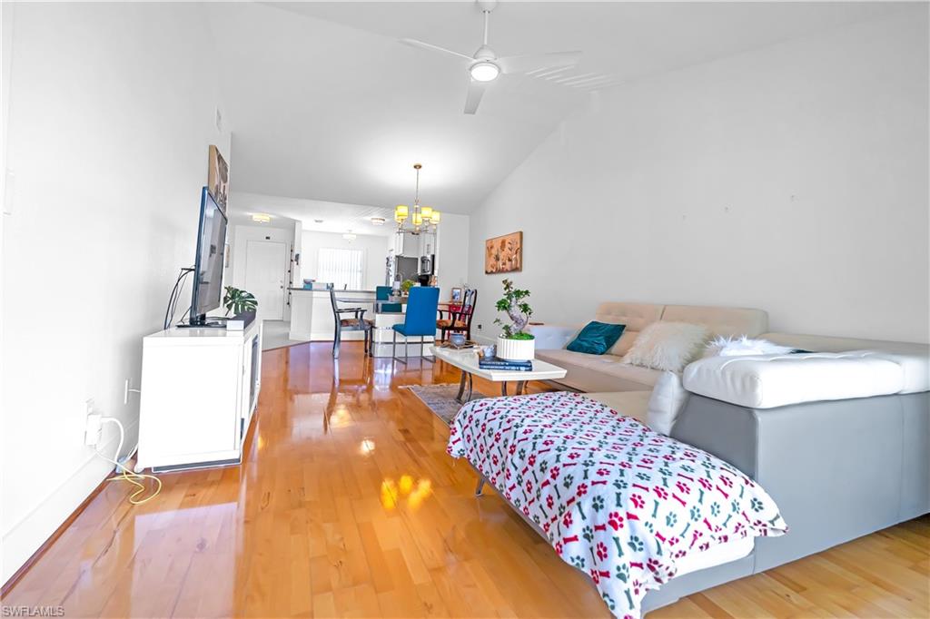 Open-concept living area featuring vaulted ceilings, wood-finish flooring, a ceiling fan, and recessed lighting