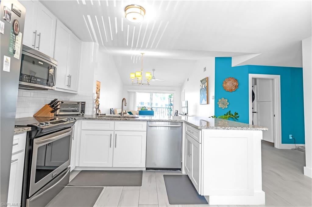 Kitchen featuring white cabinetry, stainless steel appliances, a white subway tile backsplash, and light-toned countertops