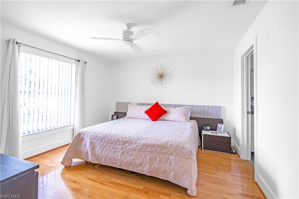 Spacious room featuring hardwood flooring, white walls, and a large window with vertical blinds