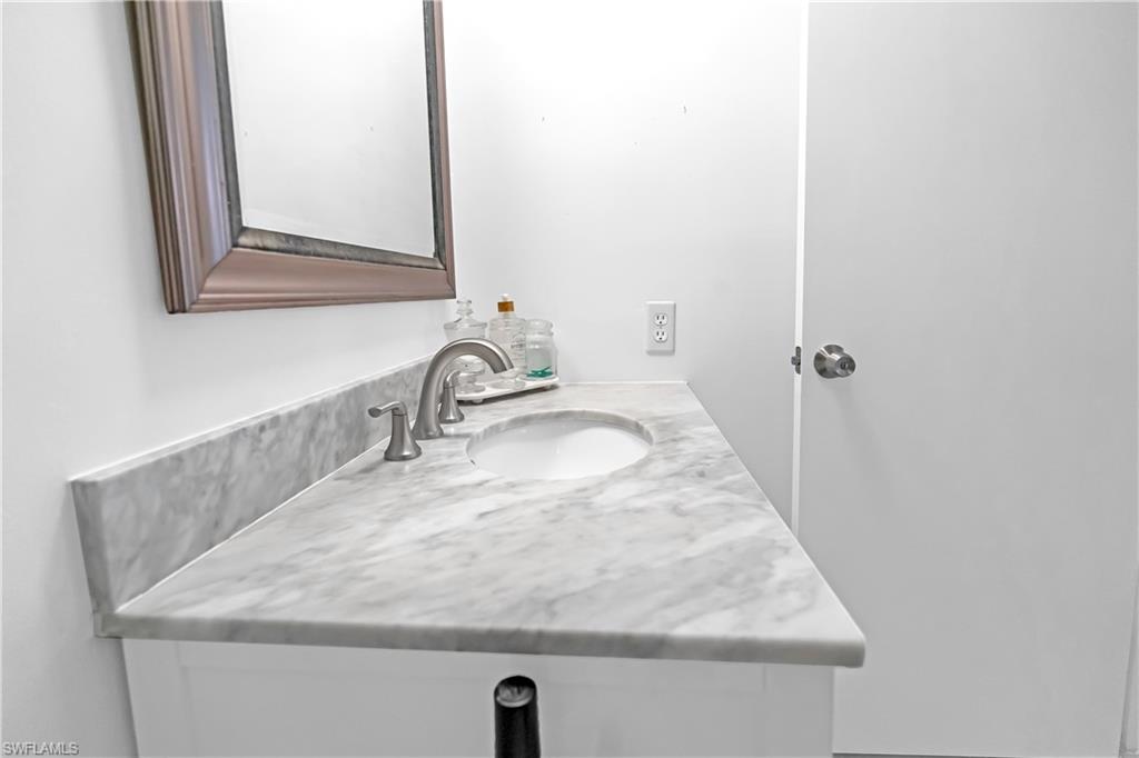 Vanity featuring a stone countertop with an integrated sink, brushed nickel faucet, and white cabinetry