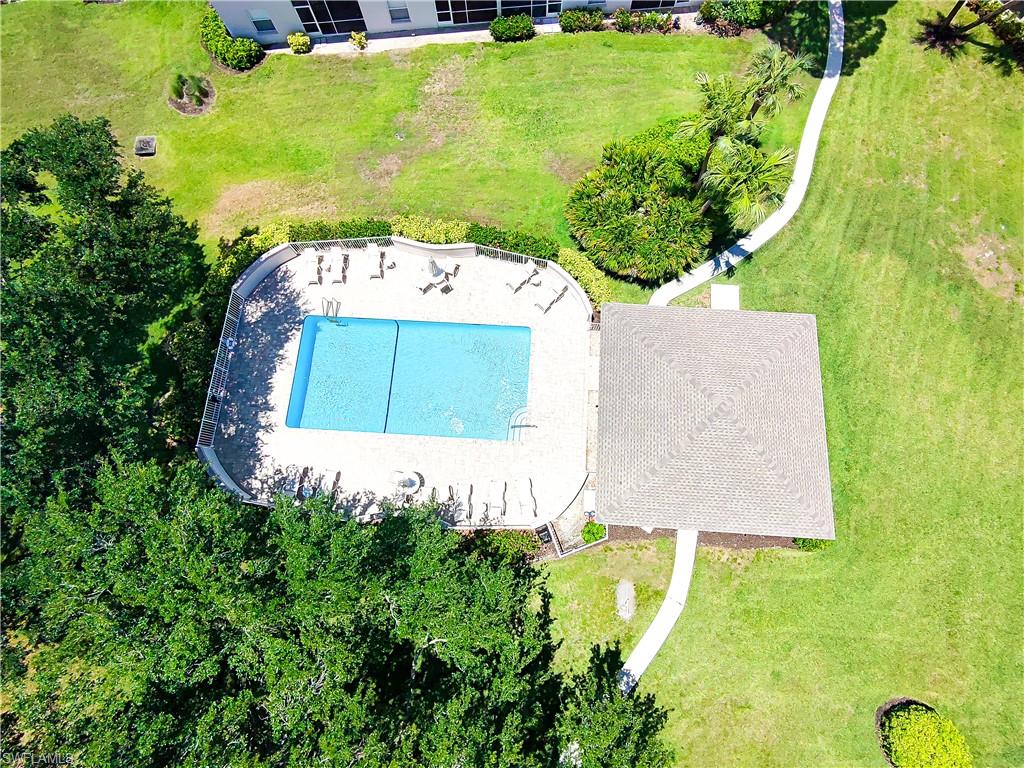 Rectangular swimming pool with a surrounding patio deck, multiple lounge chairs, and a covered poolside structure
