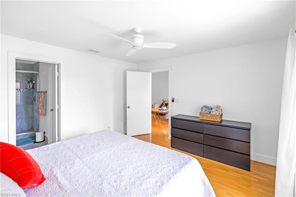 Hardwood flooring throughout, white walls, and a contemporary ceiling fan