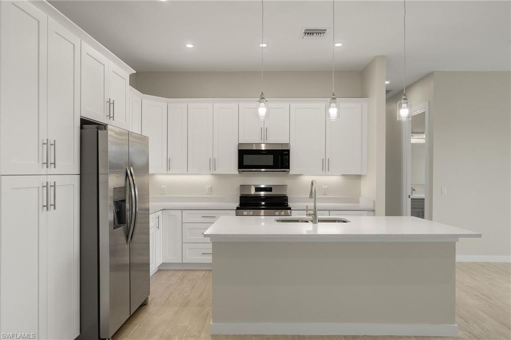 Gourmet kitchen with quartz island, shaker cabinets, and premium luxury vinyl plank (LVP) flooring upgrade.