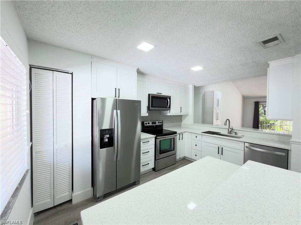 Modern kitchen featuring white cabinetry, stainless steel appliances, light countertops, and recessed lighting