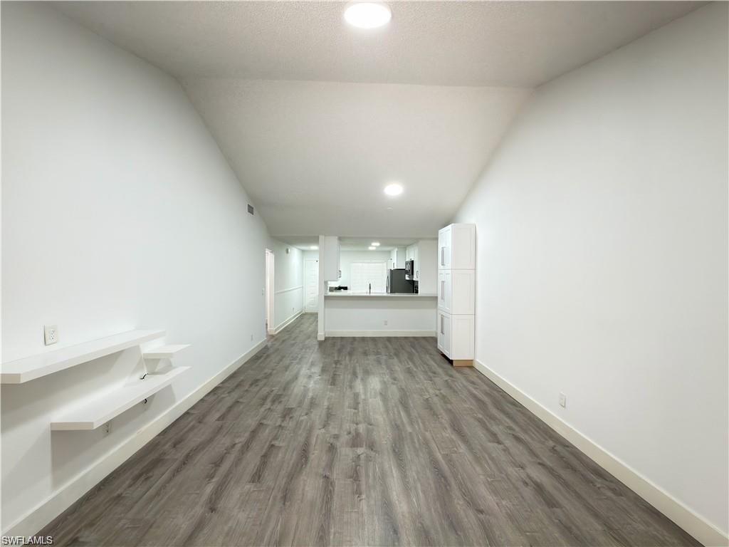 Open concept living space featuring wood-finish flooring, recessed lighting, white walls, and built-in floating shelves