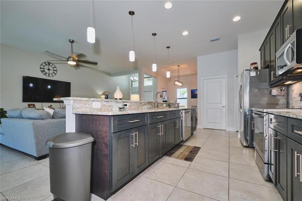 LONG ISLAND with a double sink, granite countertops, dark wood-finish cabinetry, stainless steel