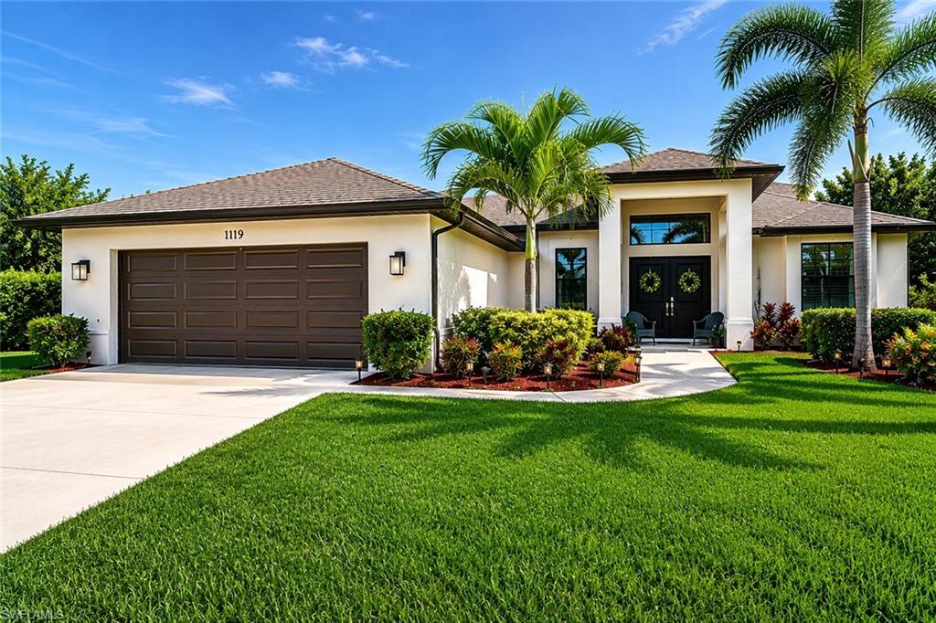 Contemporary stucco exterior with a broad concrete driveway, a two-car garage, and established landscaping