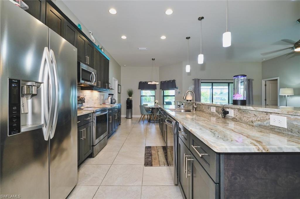 Contemporary kitchen featuring stainless steel appliances, dark wood cabinetry, and light-toned, veined countertops